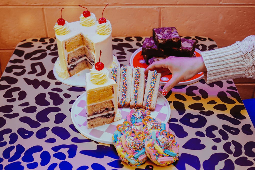 A hand reaching over at a table of desserts.